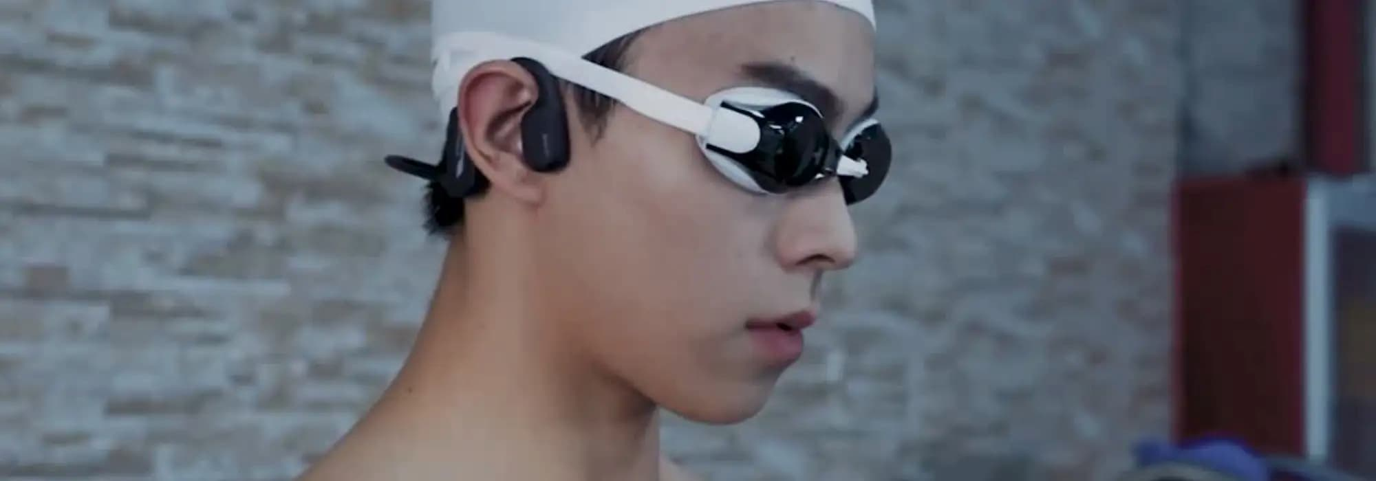 man wearing bone conduction headphones and goggles by a swimming pool