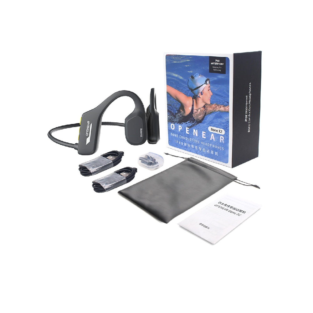 The image shows a set of bone conduction swimming headphones, the Tri-Tek Pro X2, along with its accessories which include two charging cables, earplugs, a user manual, and a soft carrying pouch. The headphones are displayed next to their packaging box which has an image of a swimmer on it.